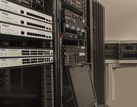 Imagem de três racks de equipamentos de rede com vários switches instalados muito bonito